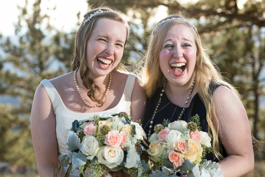 a bride and her sister laugh while holding bouquets