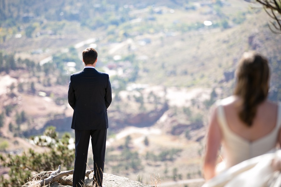 a groom faces an arid valley while his bride approaches him