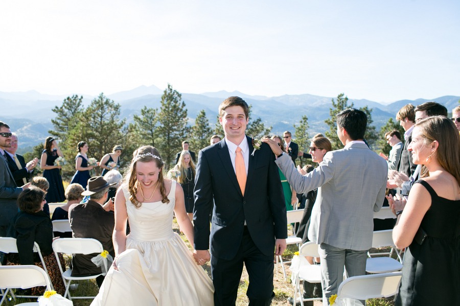 a groom and bride walk down the aisle of their outdoor mountain wedding