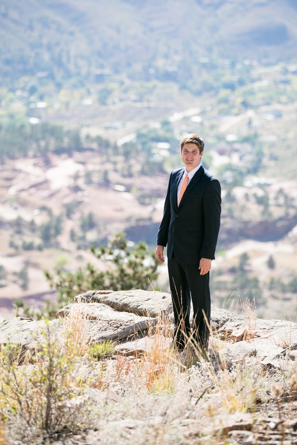 a groom stands in front of a scenic background