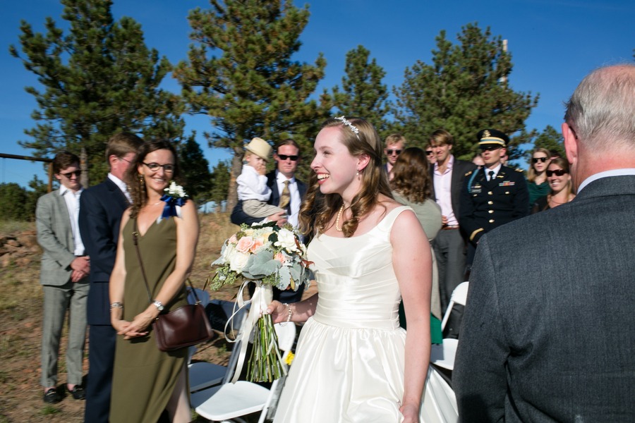 a bride walks down the aisle under colorado blue skies