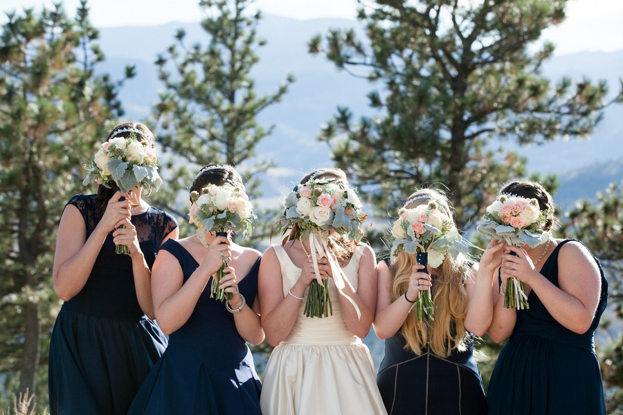 women hold bouquets in front of their faces in this bridal party photo