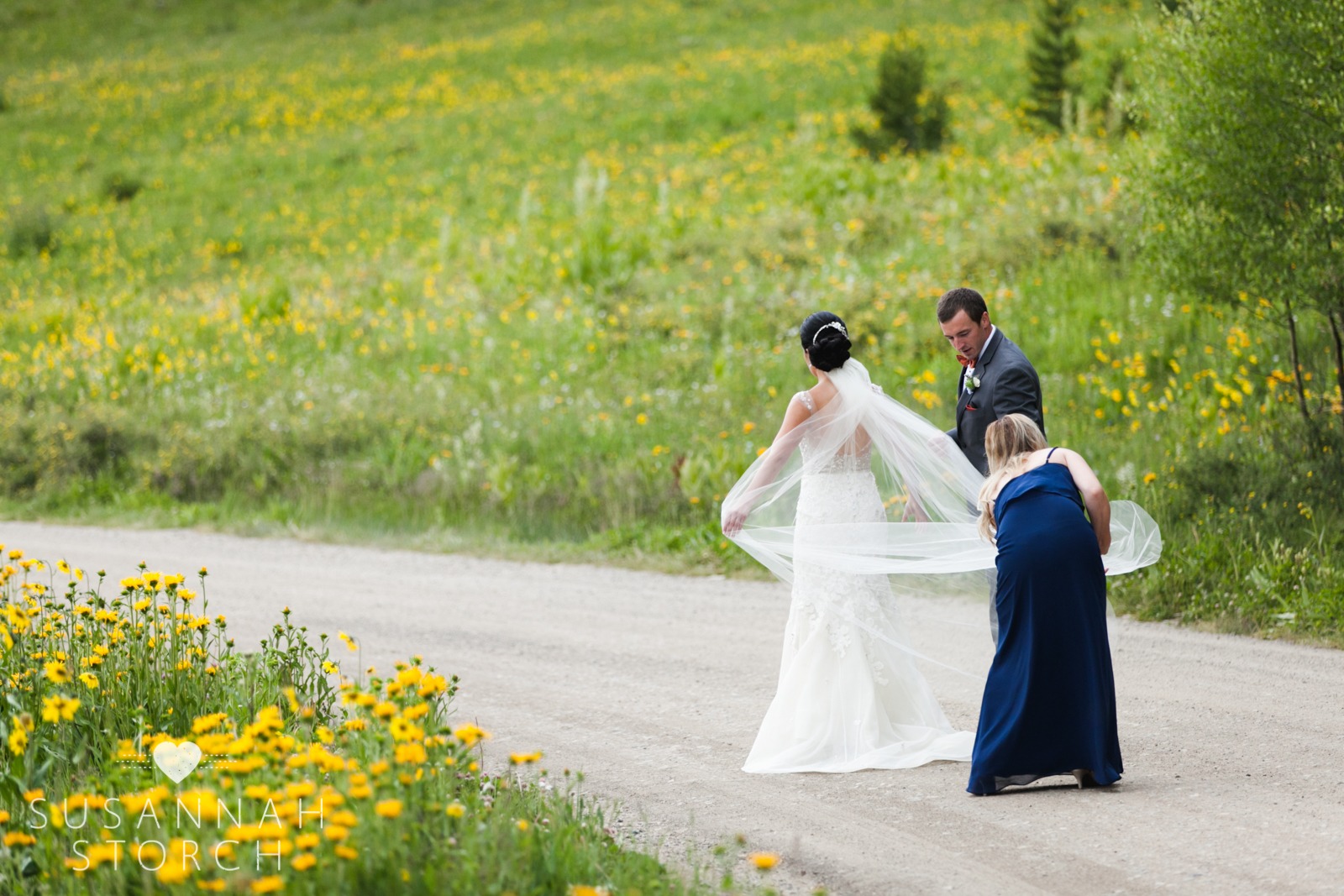 a bridemaid helps fix a bride's veil and dress