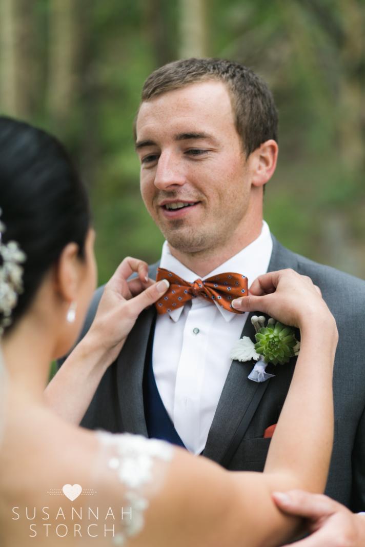 a bride adjusts her groom's bowtie