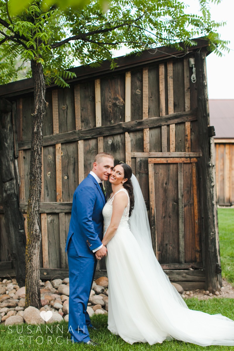 a bride and groom hold hands while standing in front of a barn