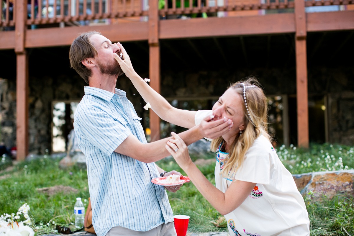 a wedding couple smear icing on each other while laughing