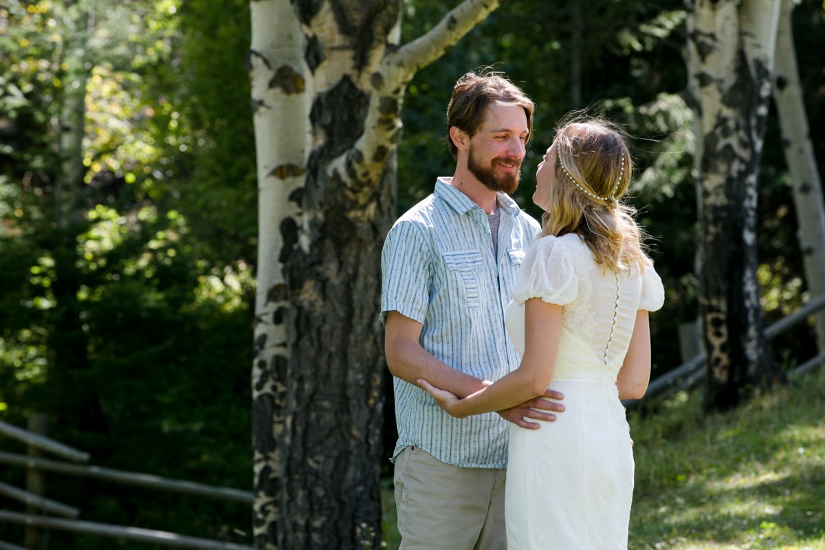 a groom stares at his new wife in front of aspen trees