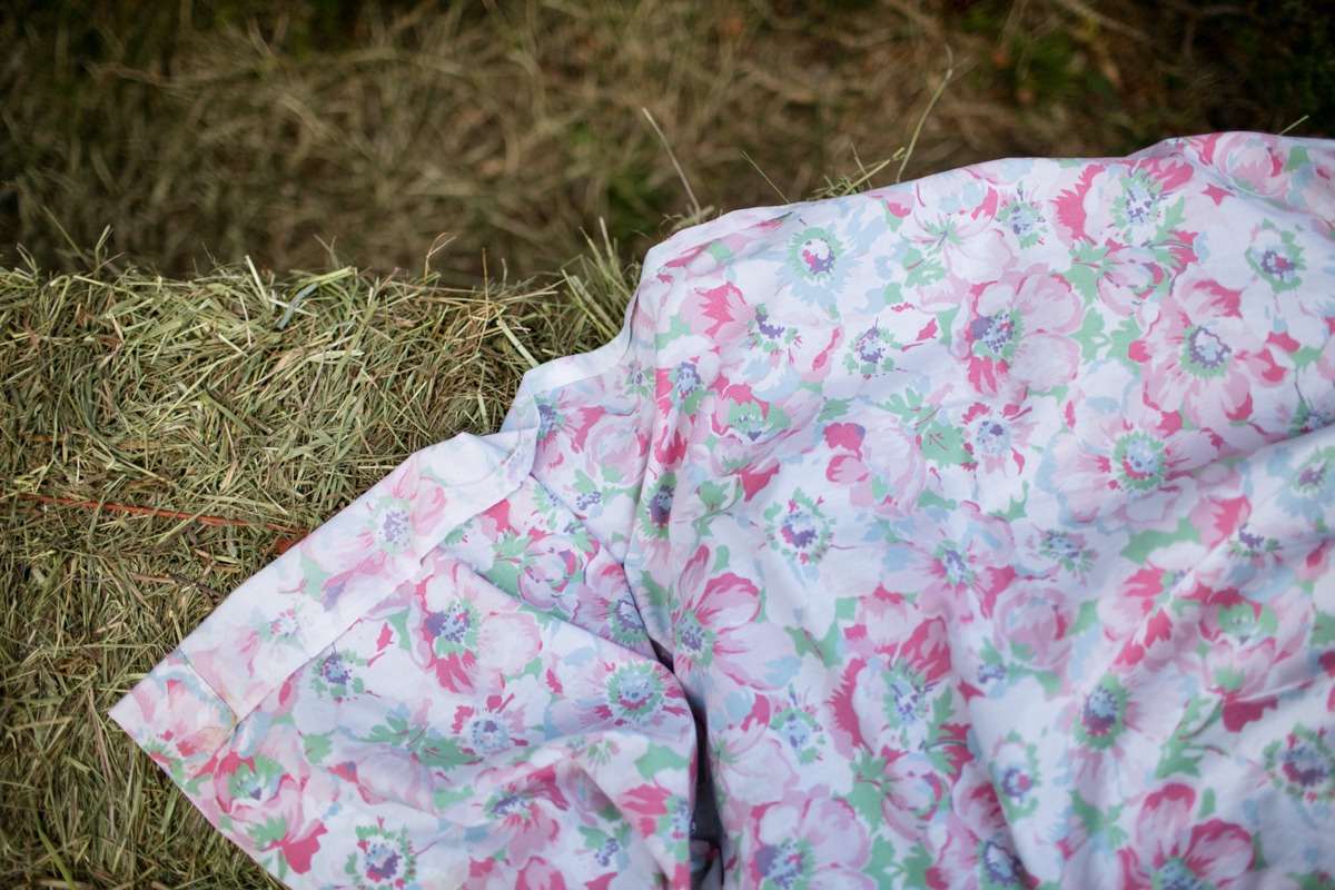 a floral printed piece of fabric lays on top of a haybale