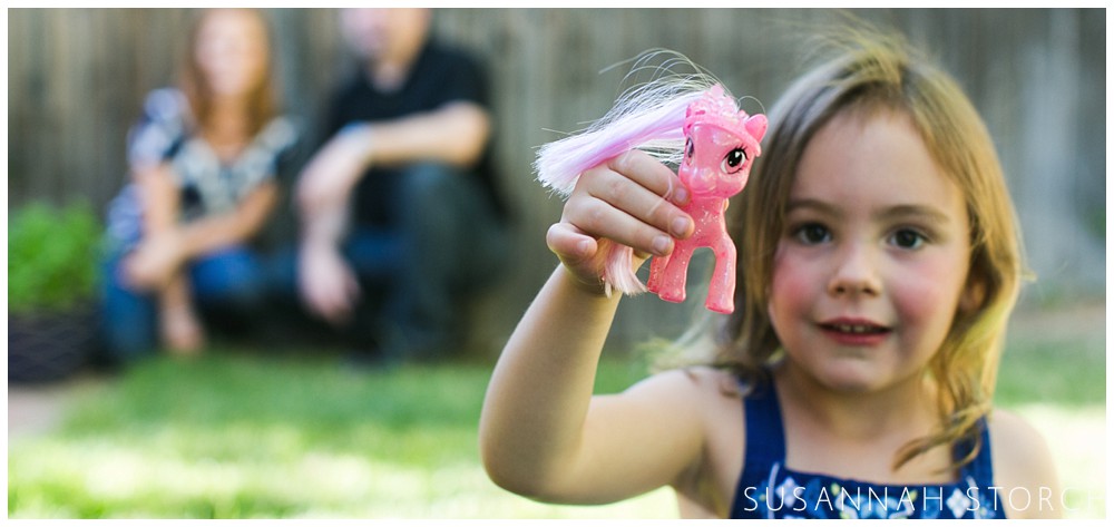 a girl holds up a pony toy