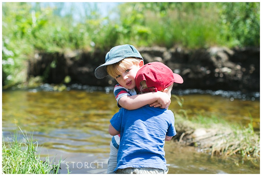 a boy in a blue hat hugs a toddler in a red hat