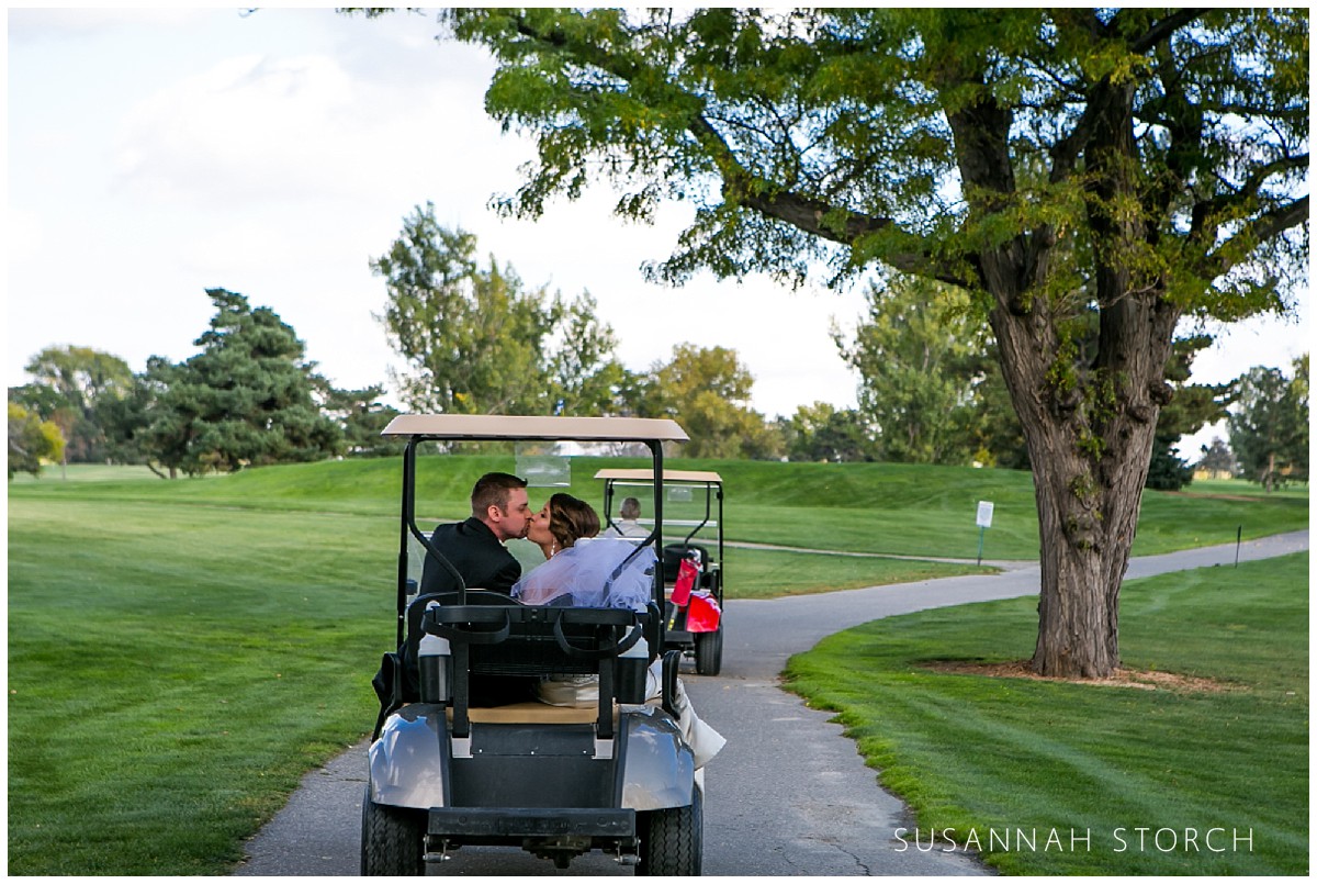 bride and groom kiss while in a golfcart