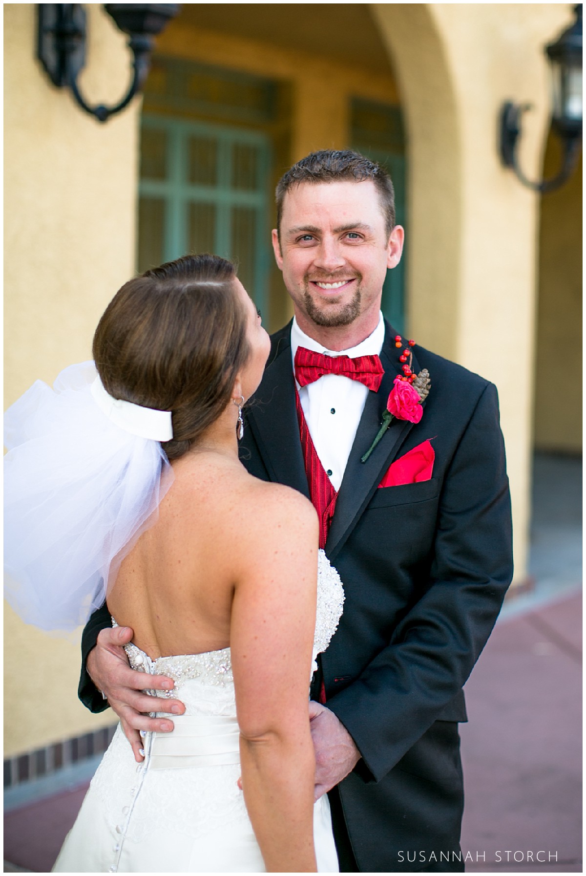 a groom wearing a red bowtie smiles
