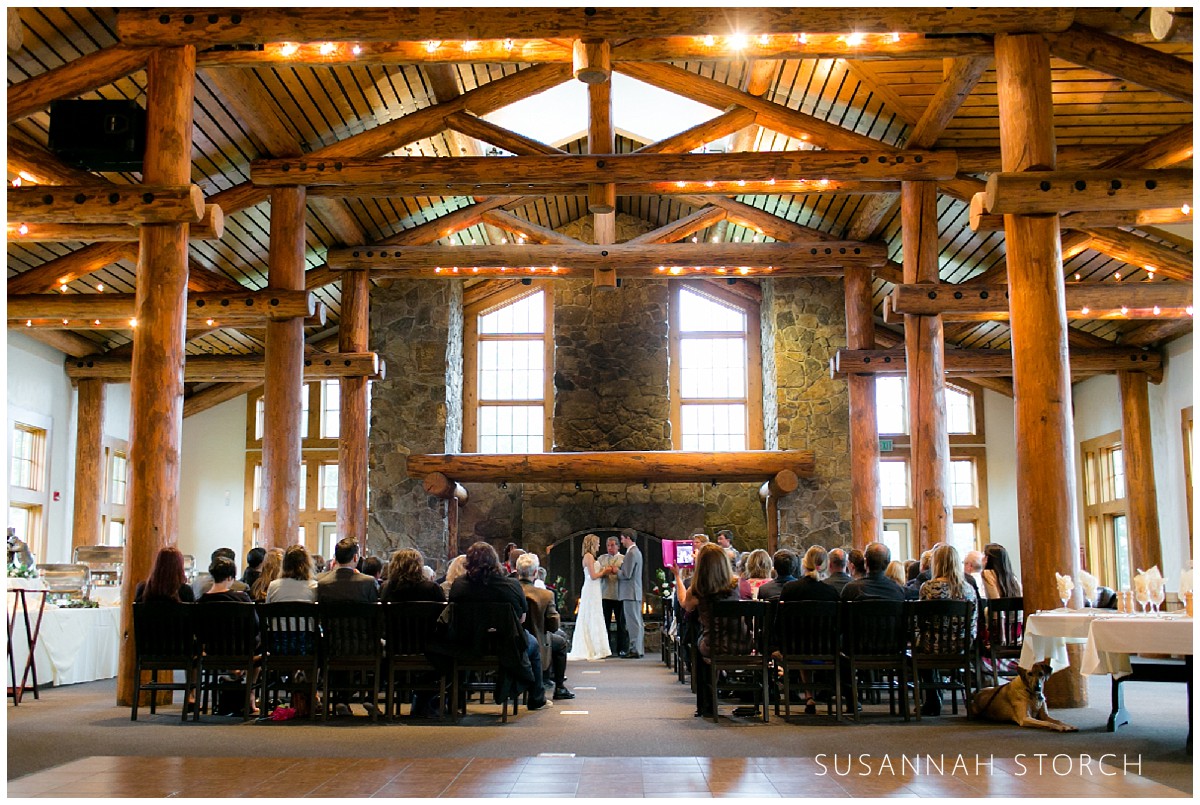 a couple gets married in a big room in front of a fireplace