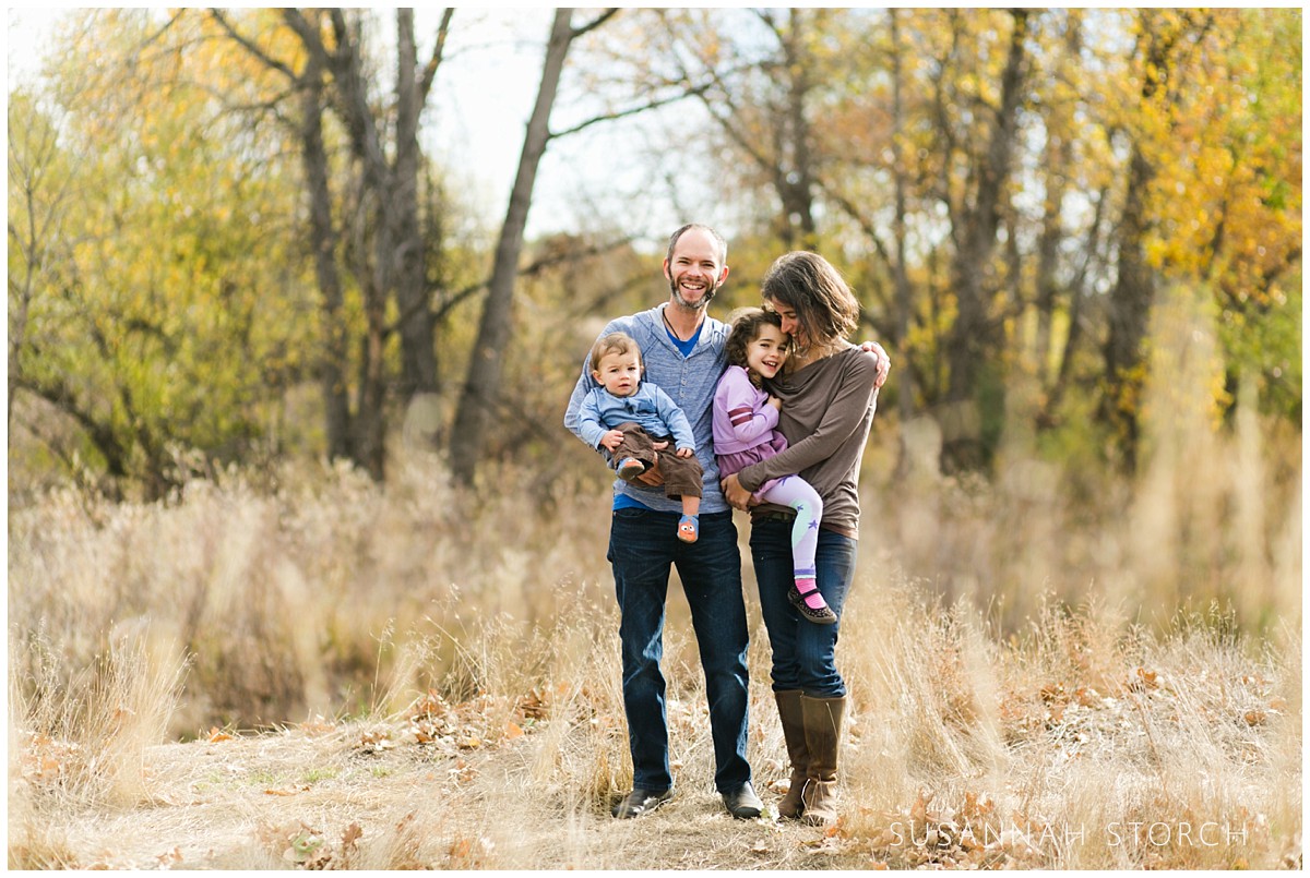 a family stands in front of fall trees