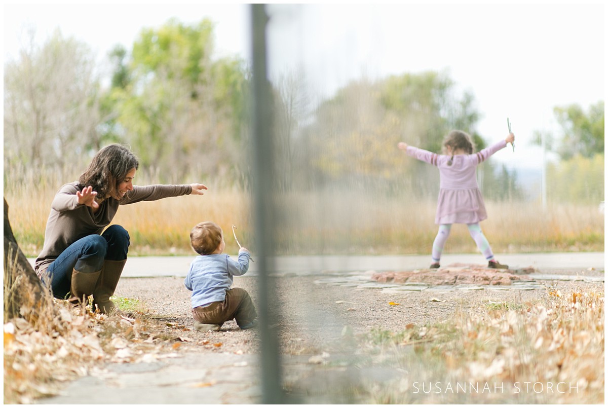 a girl plays while her little brother and mom watch
