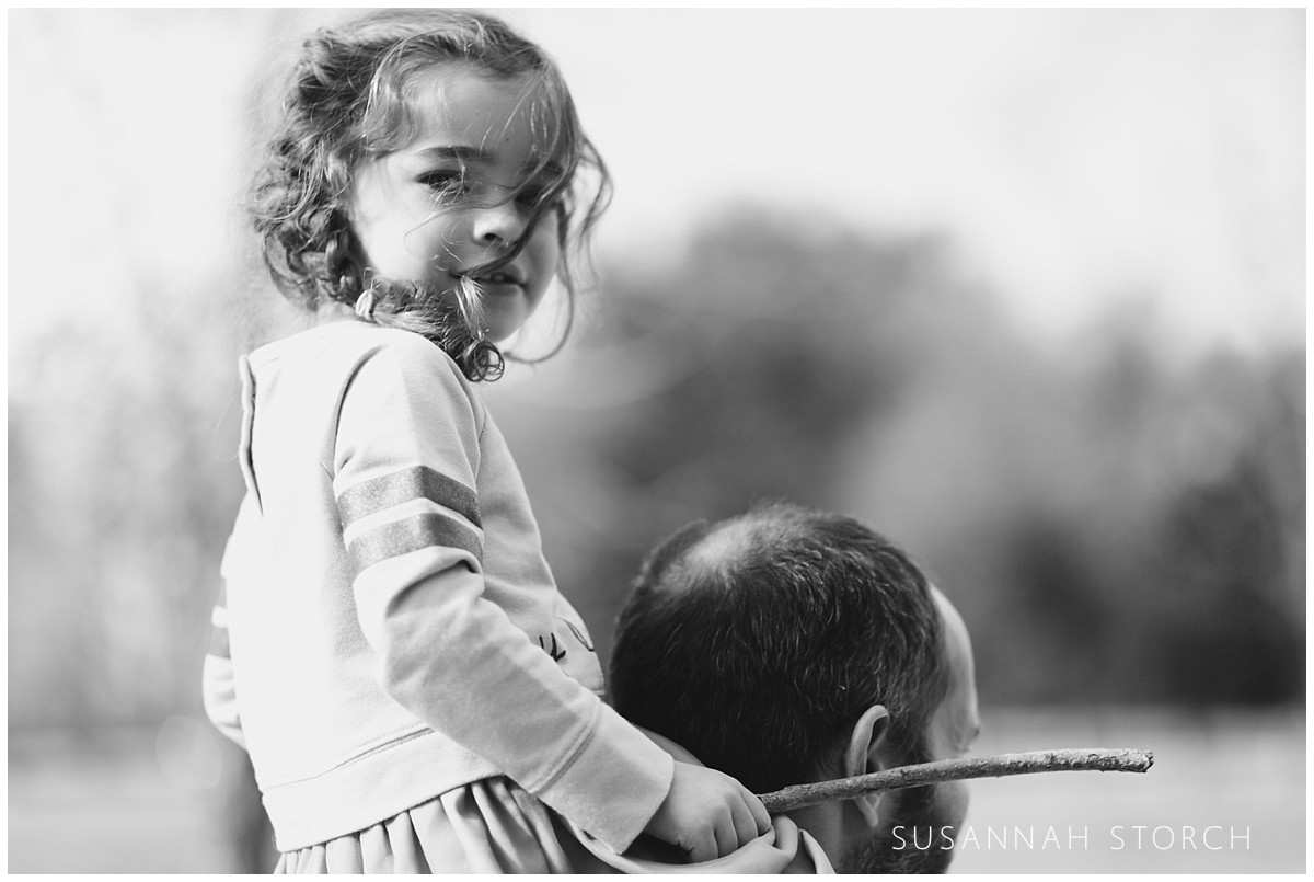 black and white of a girl riding her dad's back