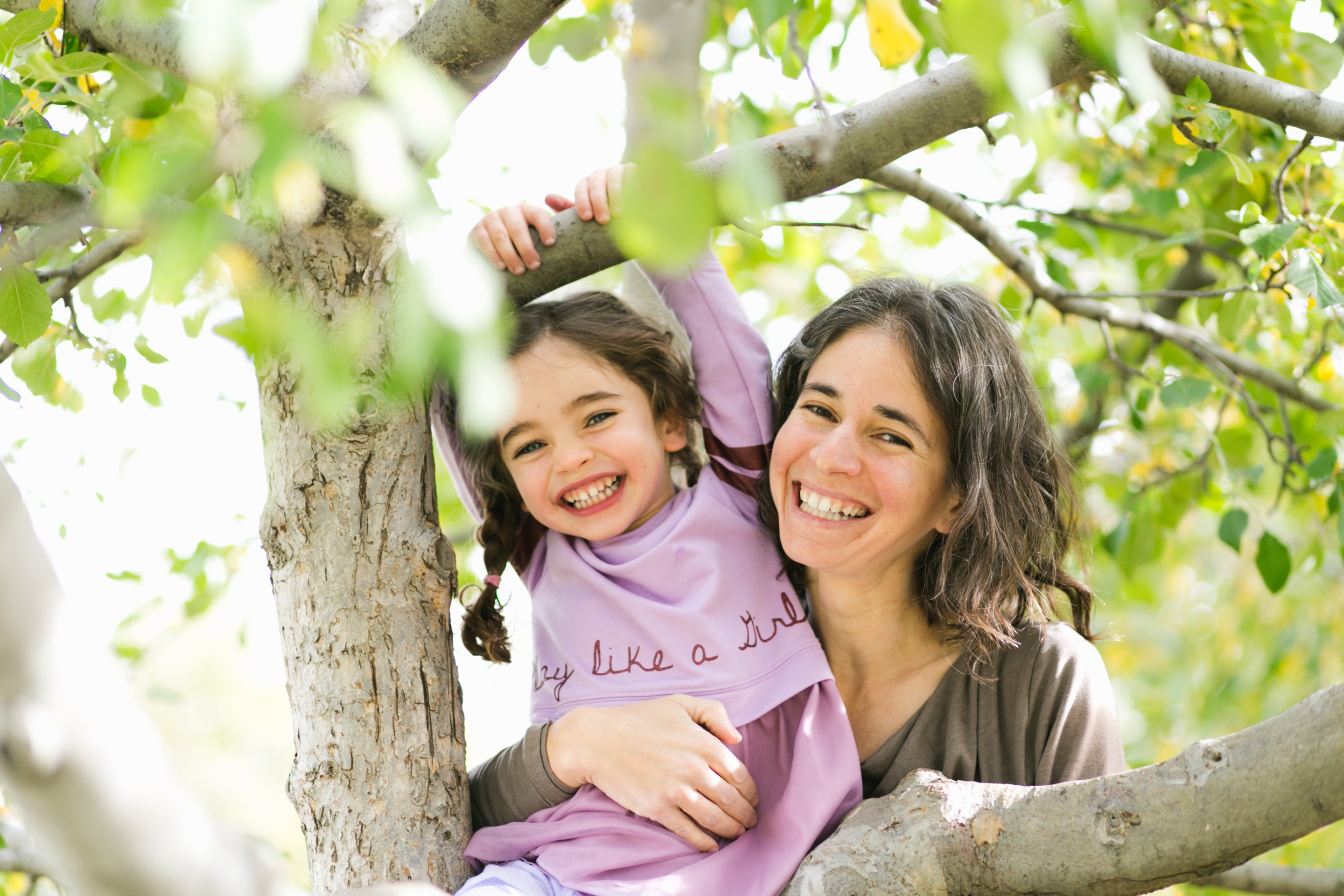 a mom and daughter smile while hanging out in foliage