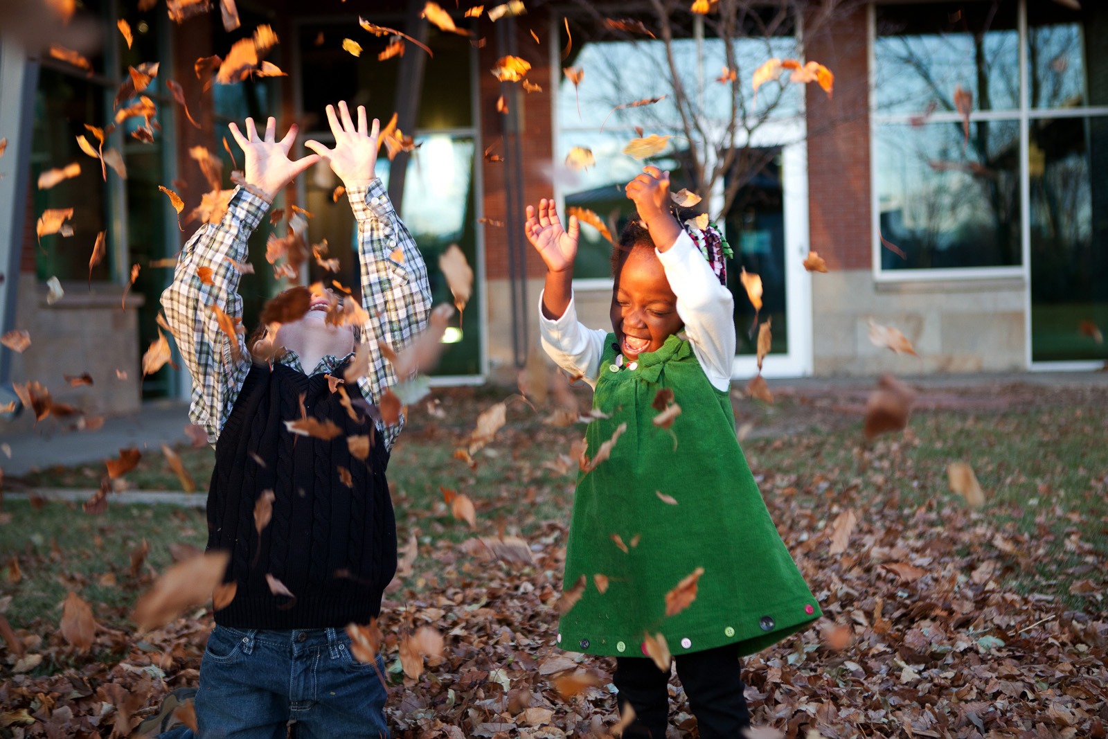 a brother and sister play in leaves during a longmont colorado familly photoshoot
