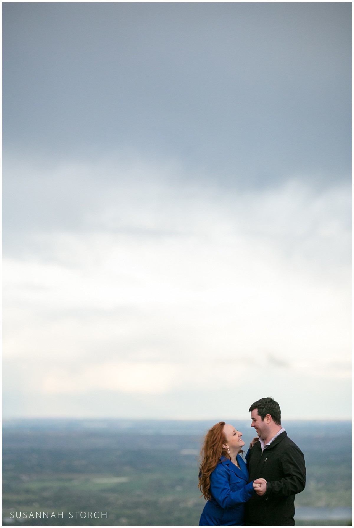 an engaged couple looks at each other under stormy skies