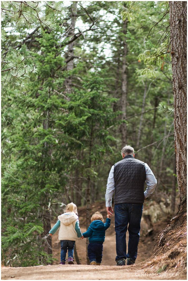dad and children hold hands while hiking in a boulder colorado forest