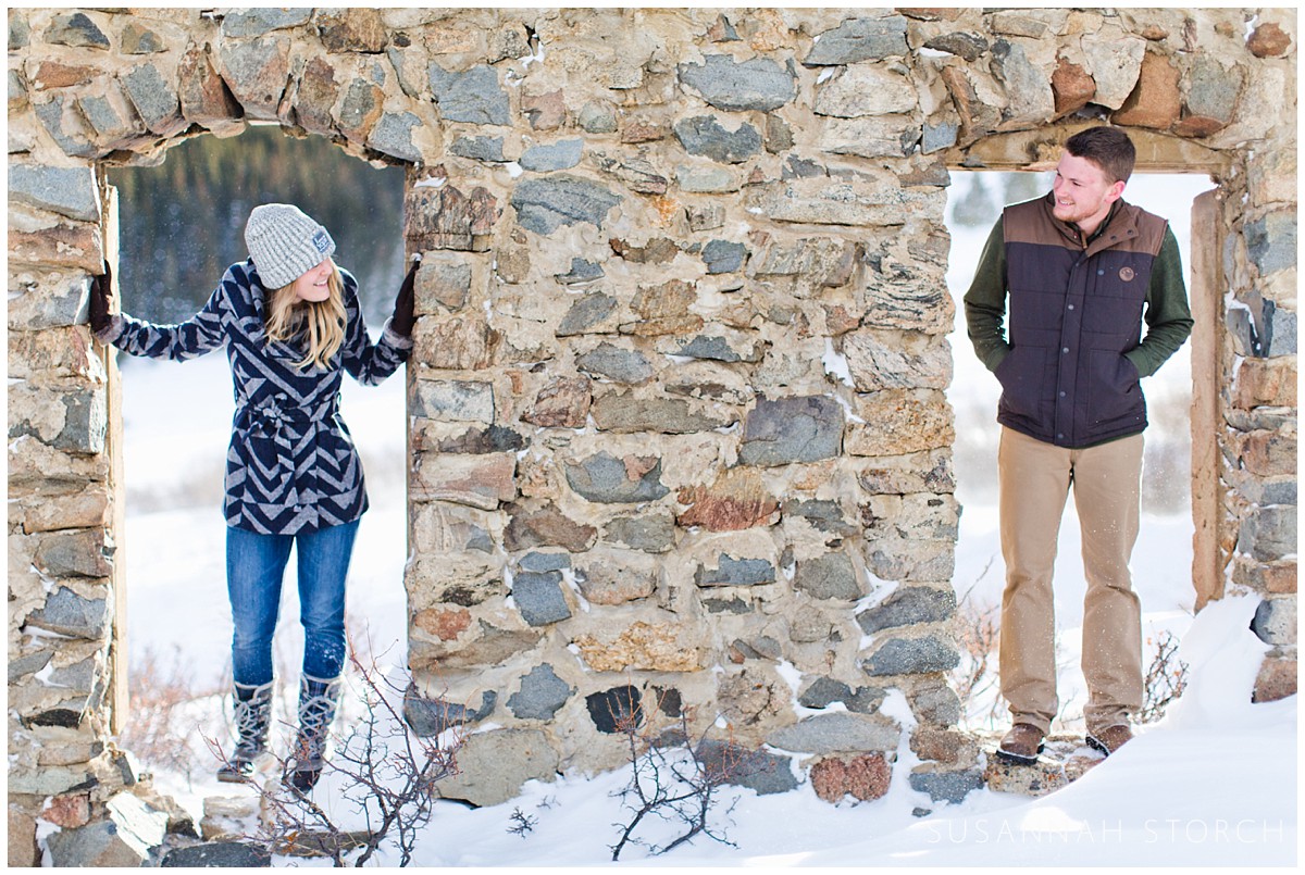 a man and woman look at each other from doorways in an old rock wall