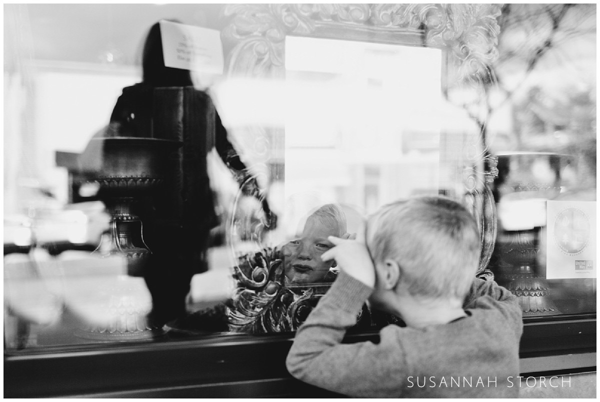 a boy looks into a mirror in a store window
