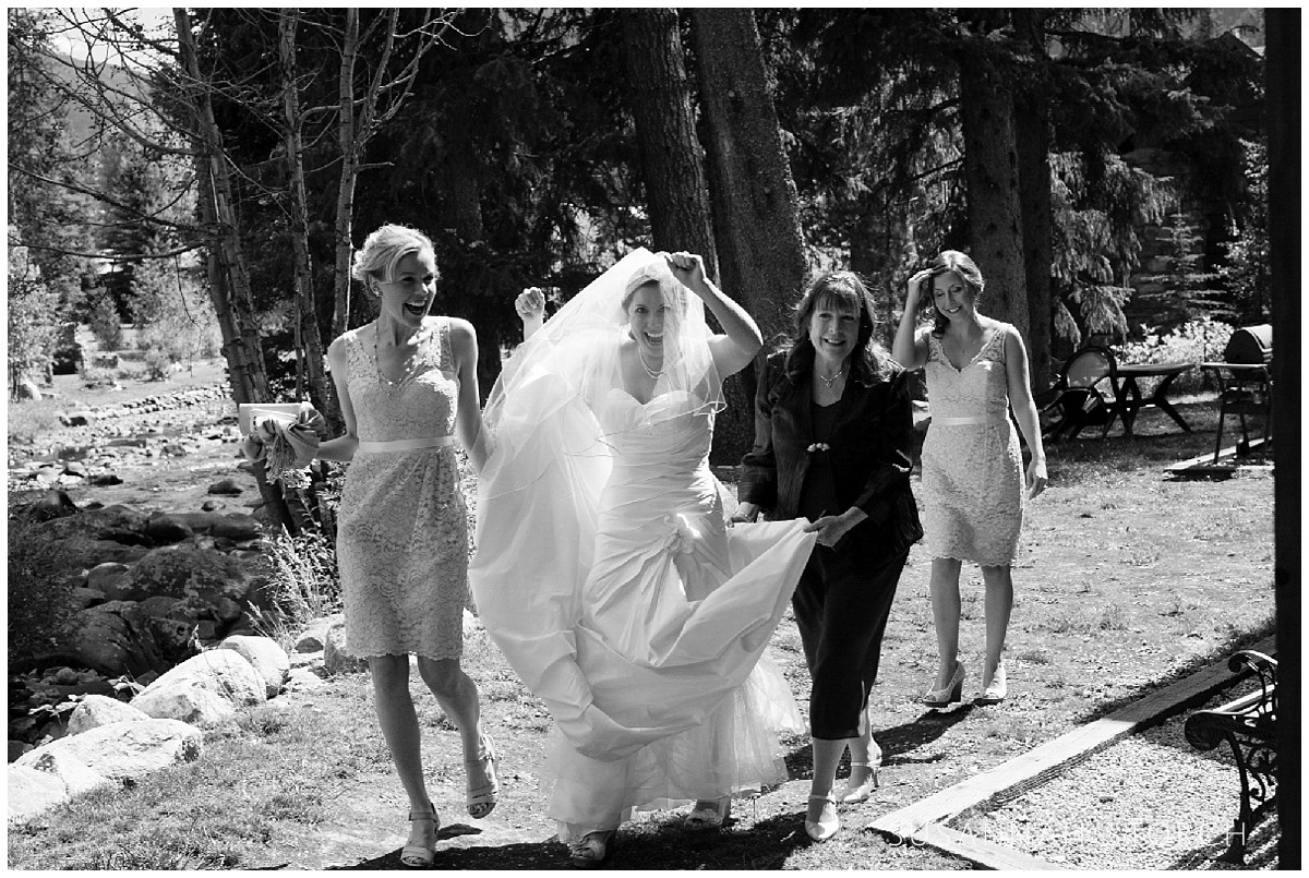 black and white image of a bride walking in front of her mom and bridal party