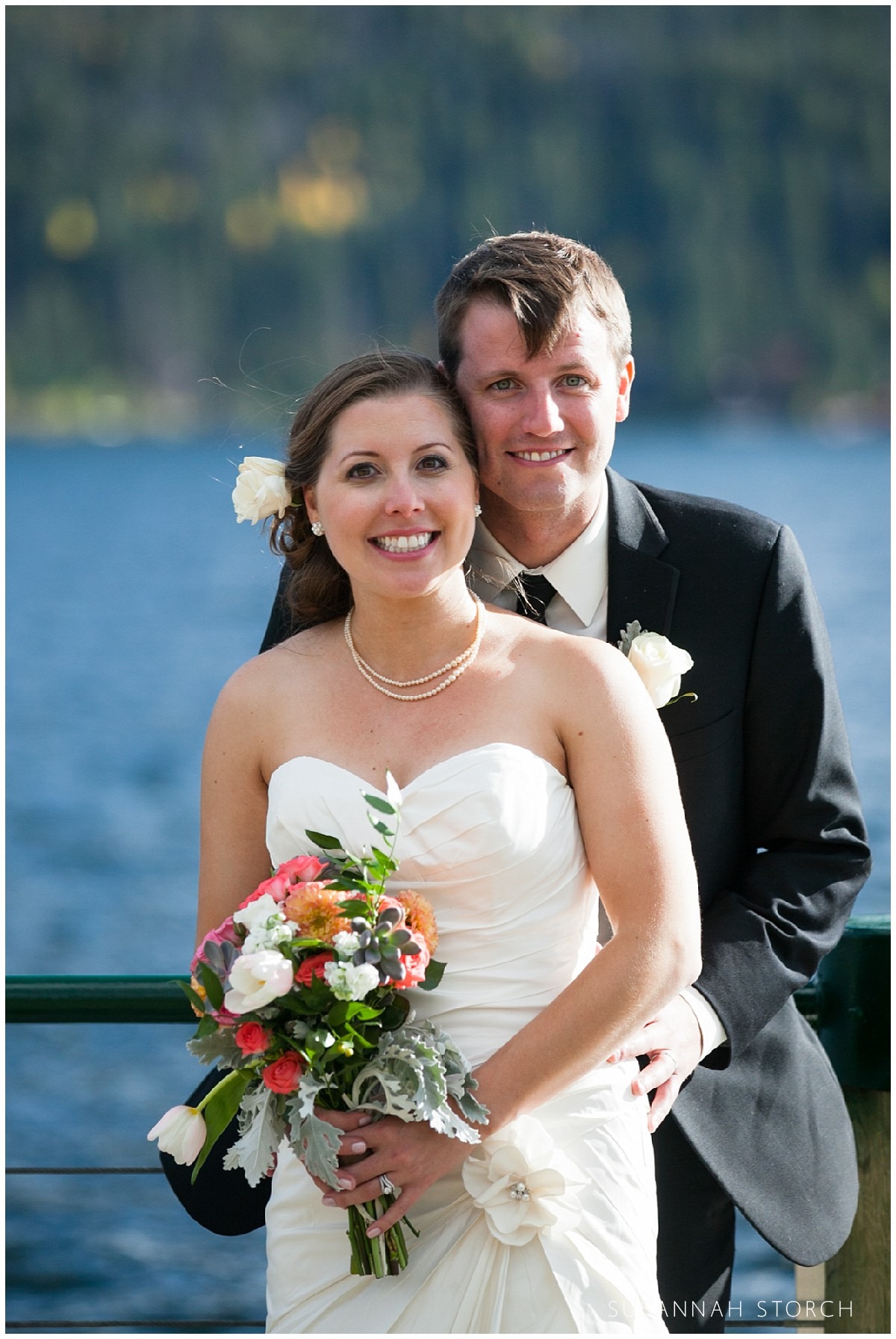 a bride and groom pose for a formal portrait with a lake in the background