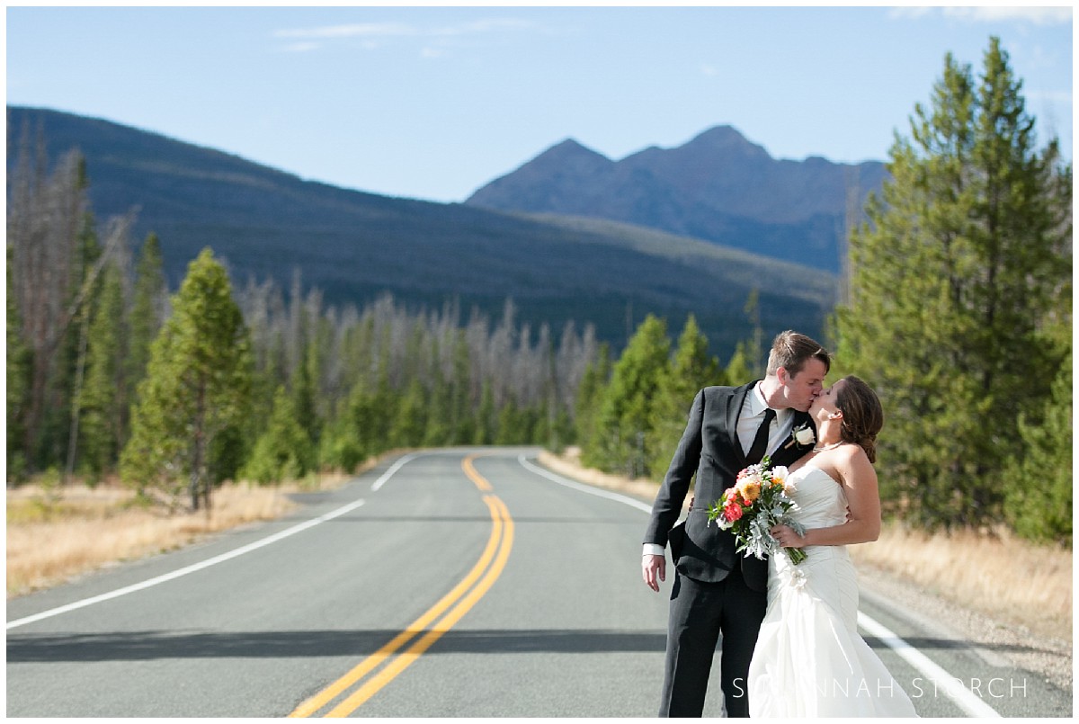 a wedding couple kiss in front of mountains