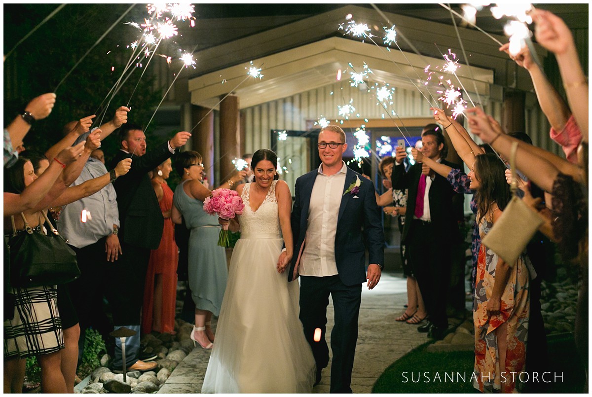 a bride and groom walk through sparklers