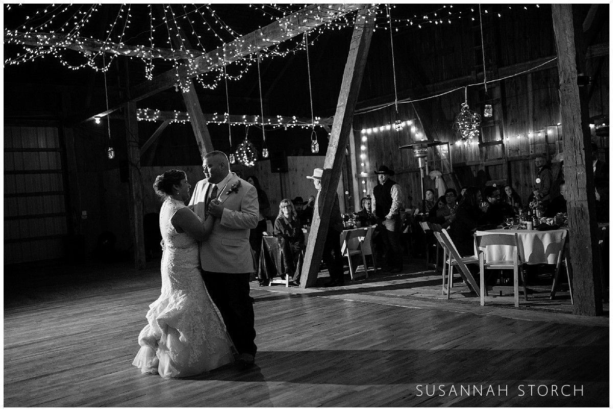 a wedding couple dancing in a barn