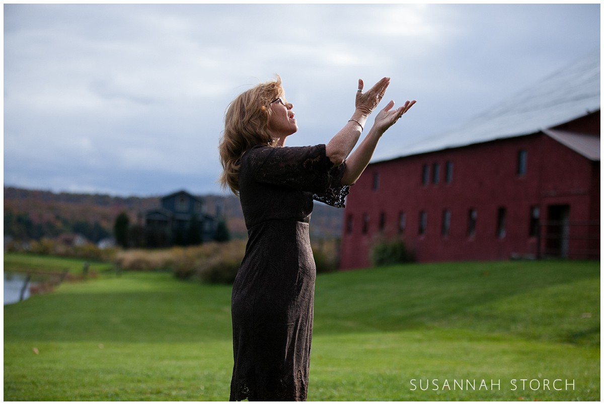 a woman performs sign language at an outdoor barn wedding ceremony