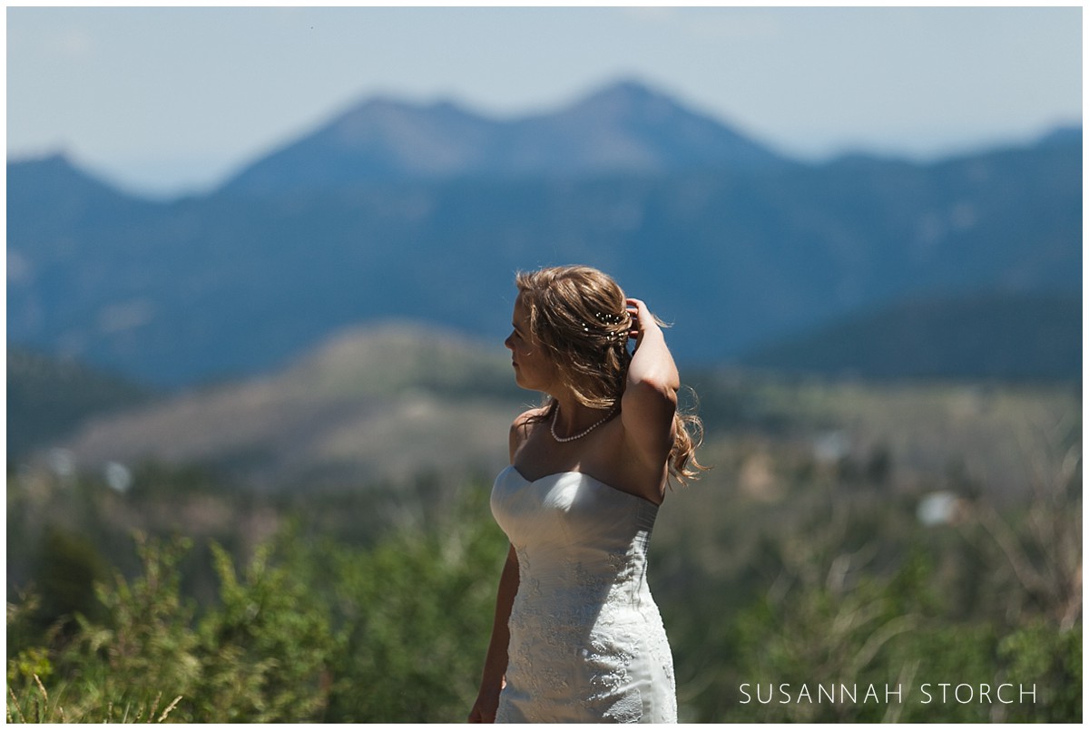 a bride moves her hair while standing in front of mountains