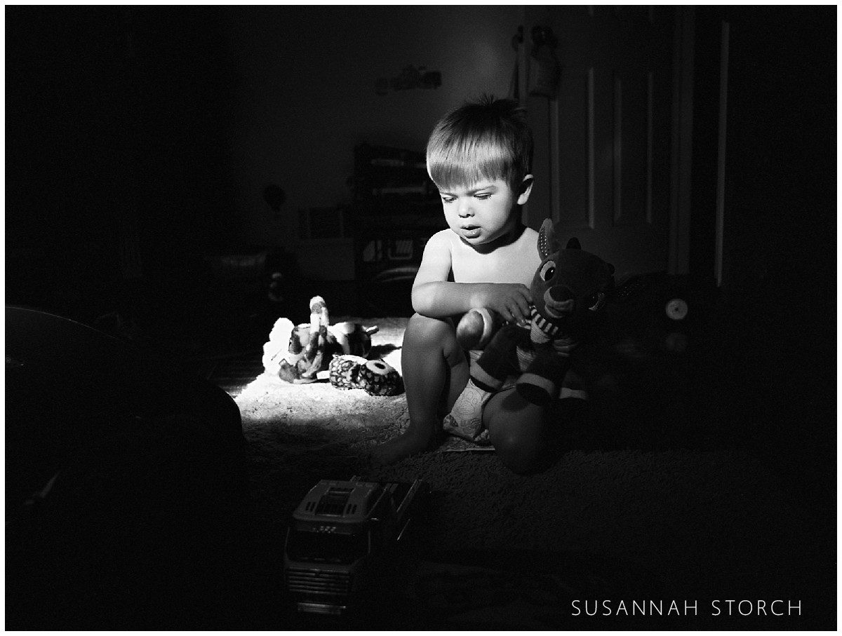 black and white portrait of a young boy playing with toys