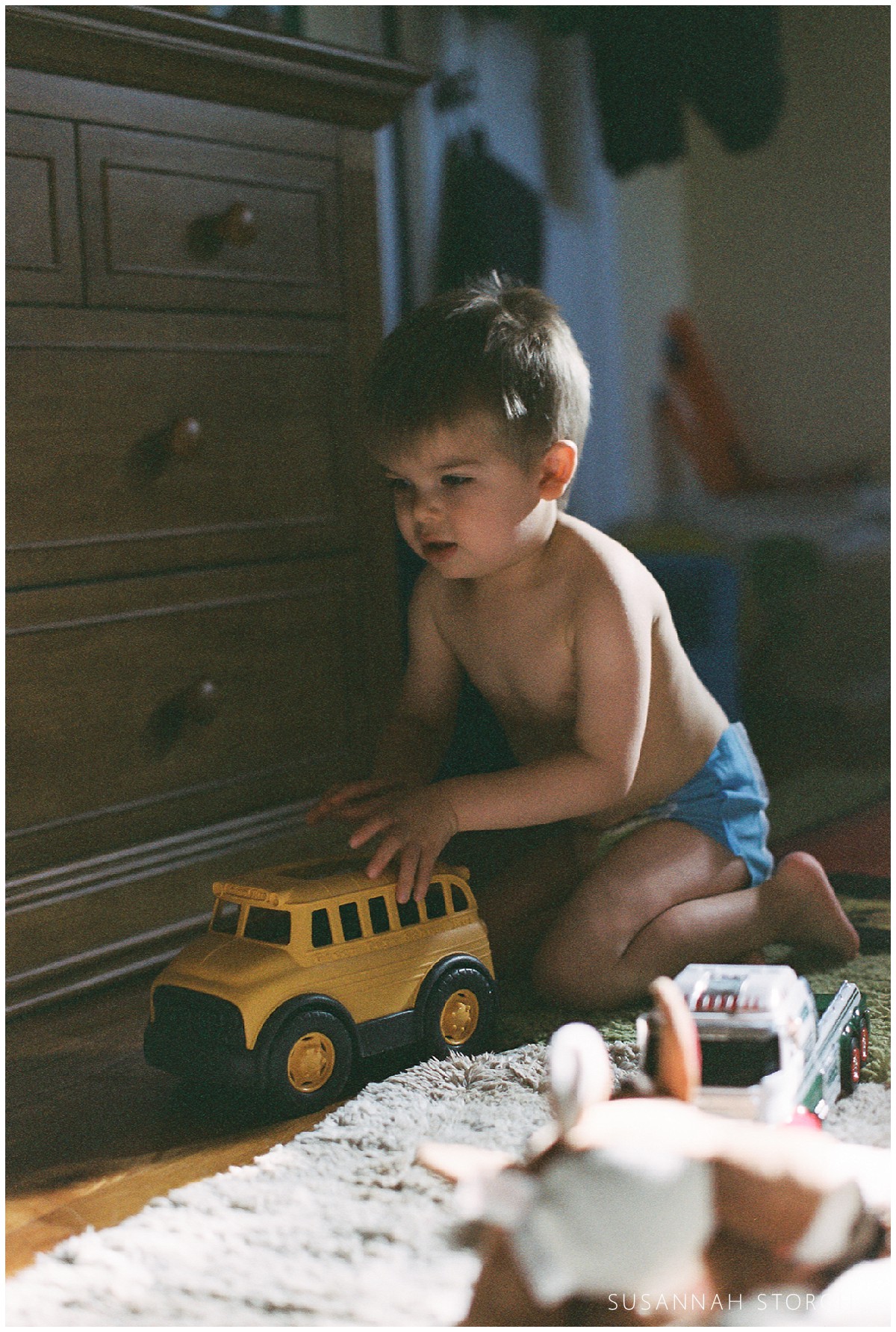 A boy plays with a toy bus during a family lifestyle session