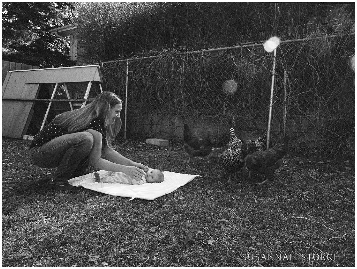 black-white film photo of chickens near a baby
