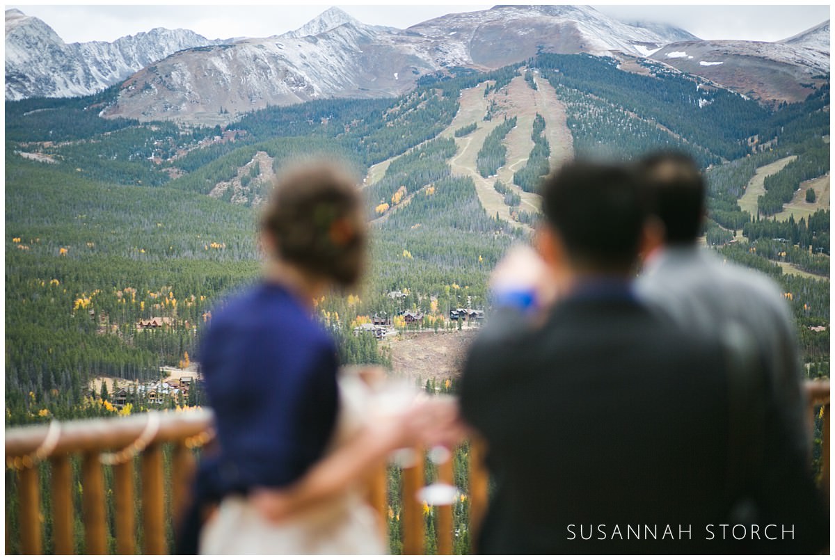 a bride and her guests stands on a deck that overlooks the breckenridge ski resort