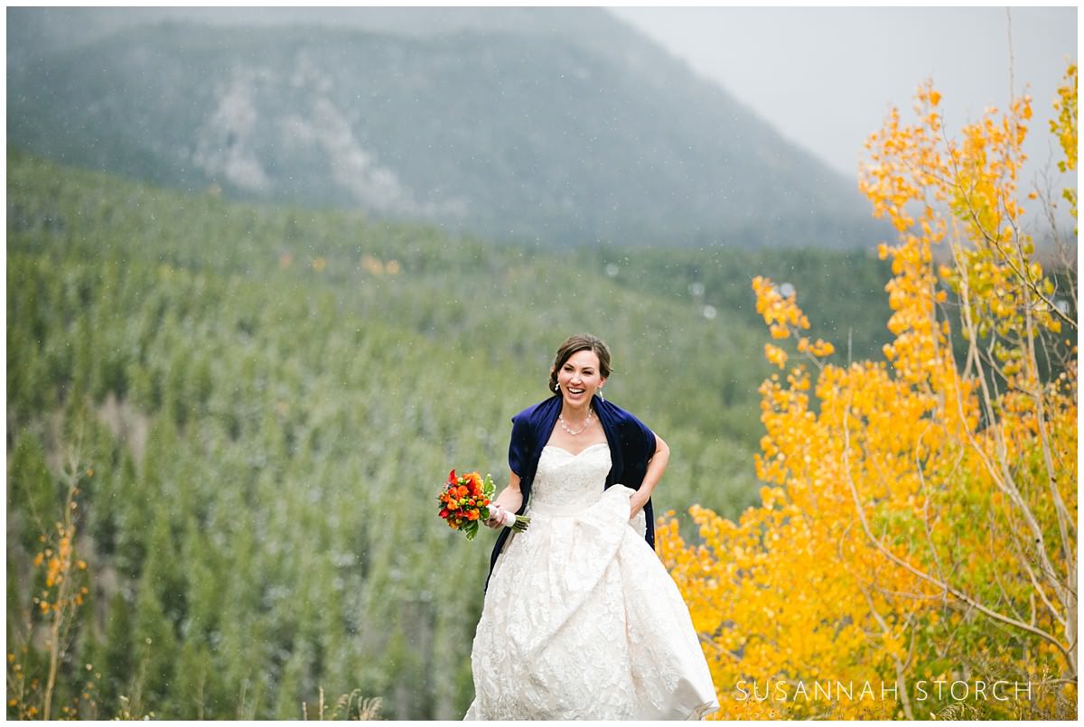 a bride walks up a hill on a fall day in the mountains of colorado