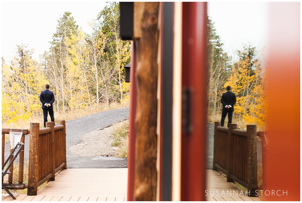 a groom stands on a concrete path waiting to see his bride
