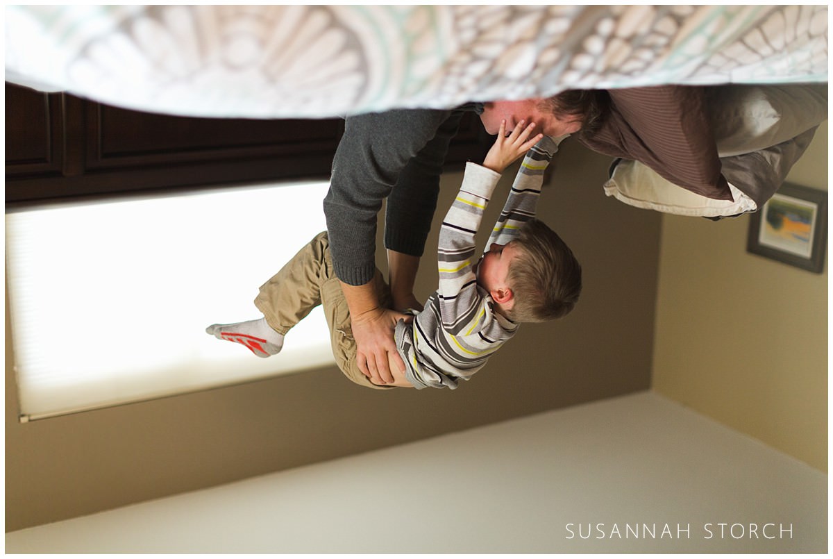 a dad lifts his son into the air in this upside-down photo