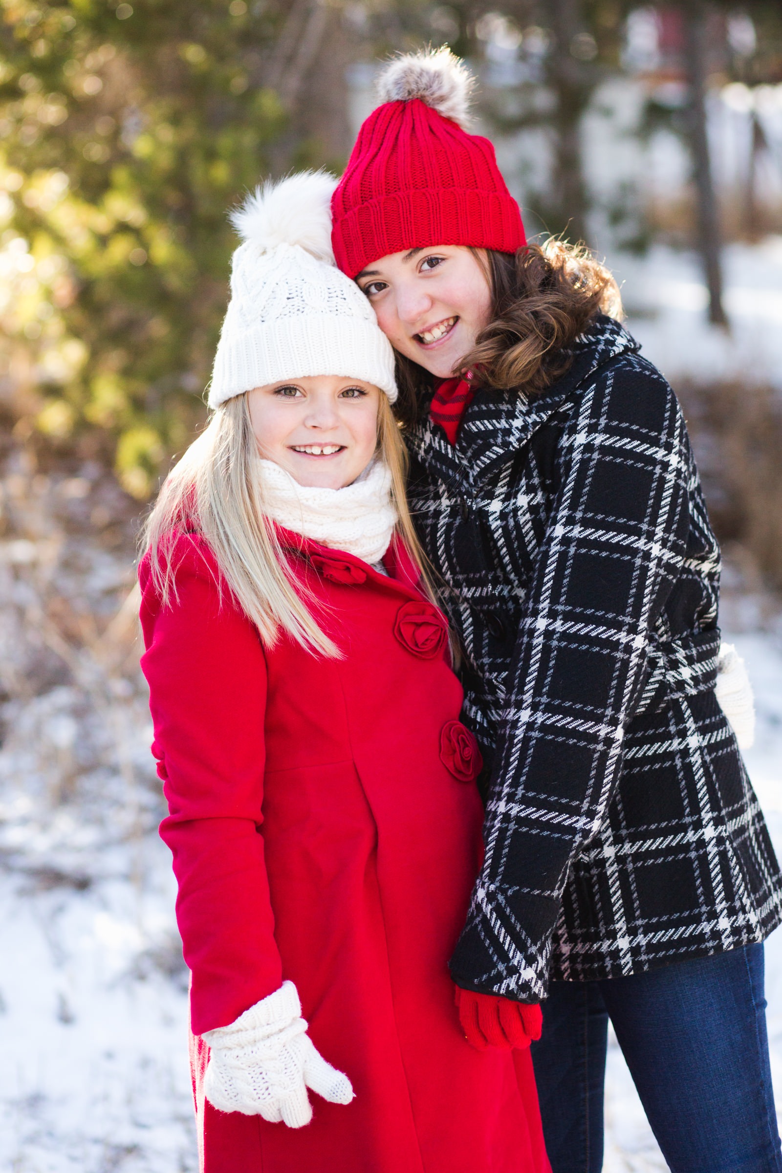 two sisters in bright winter outfits pose for the camera