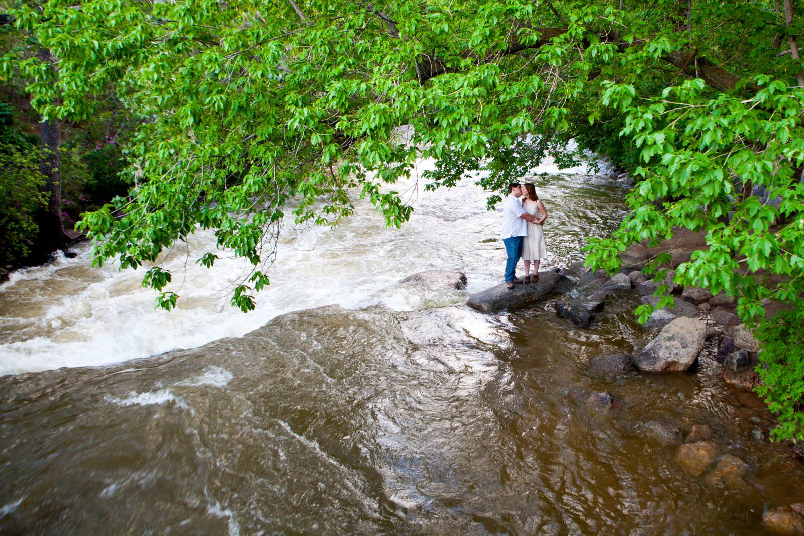An engaged couple pose along the Boulder Creek.
