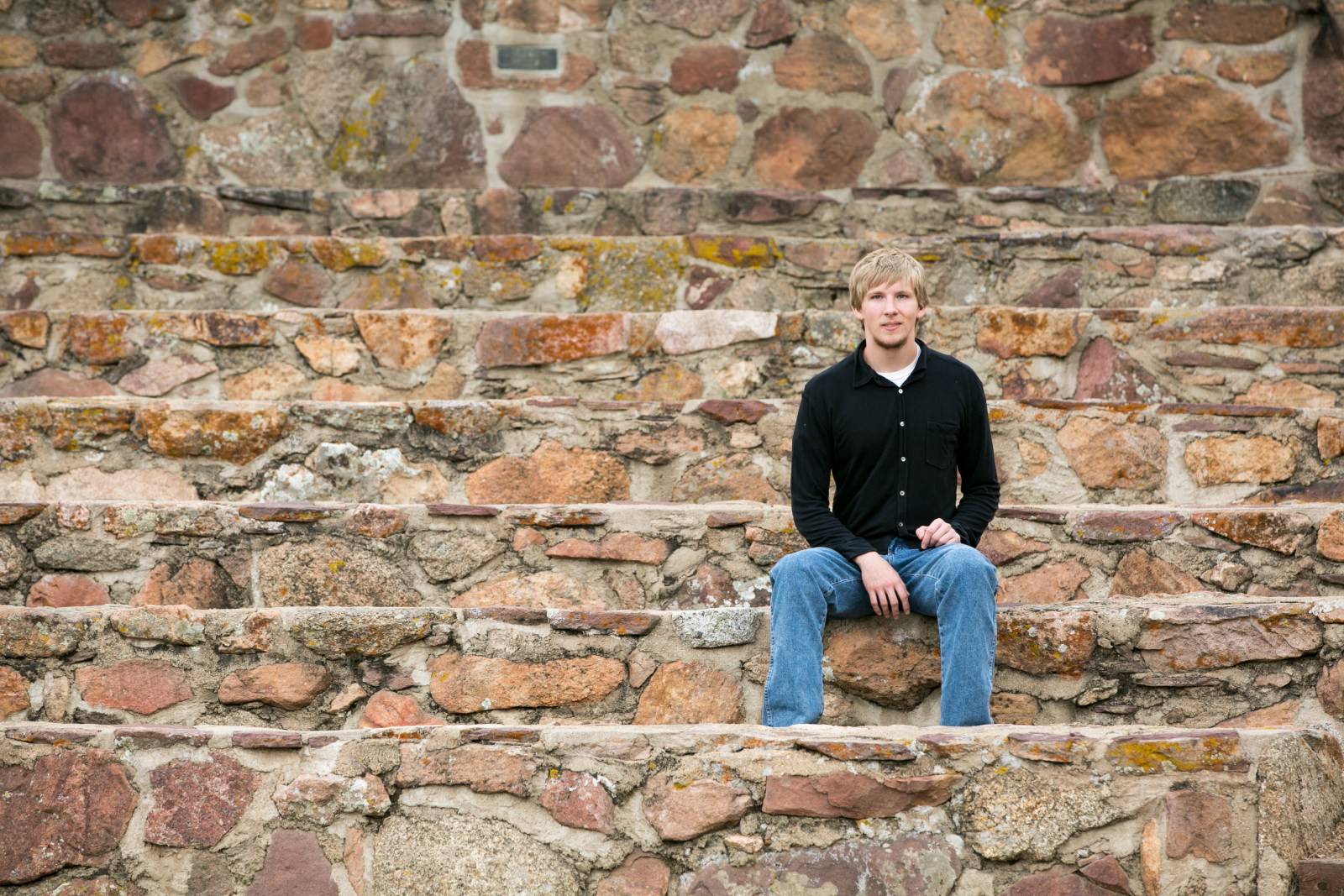 a young man sitting on rock steps in boulder, colorado