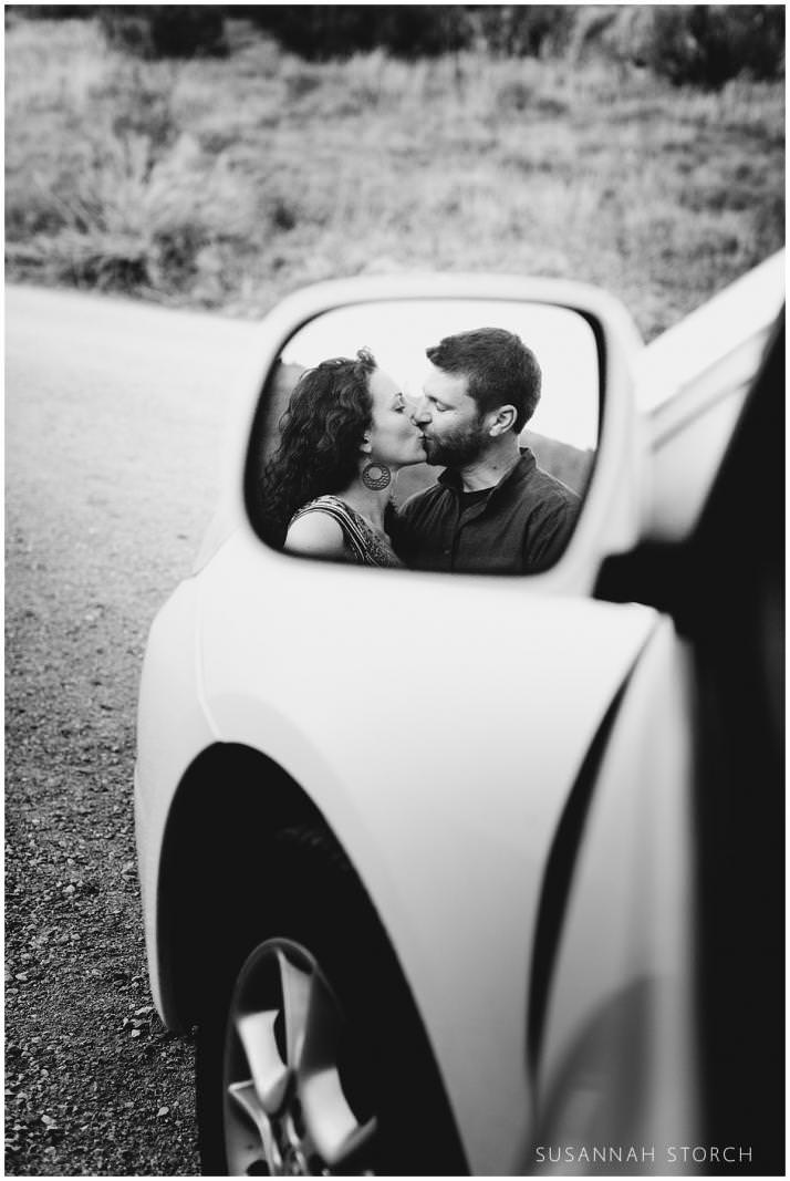 a kissing couple's reflection is shown in a car mirror