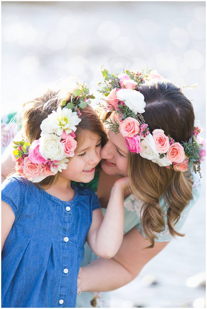 snuggling mom and daughter wearing floral crowns