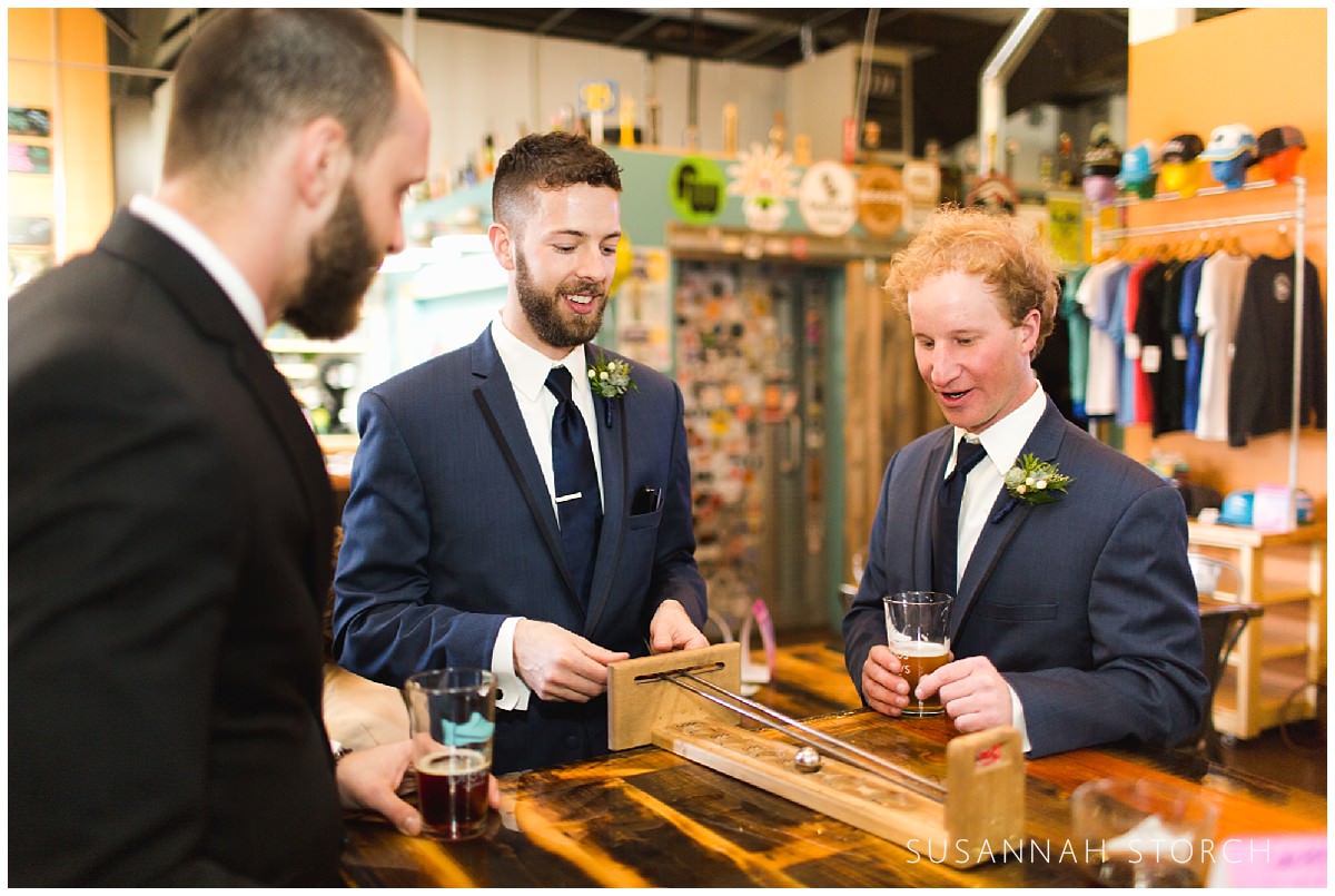 Groomsmen play games at a brewery during a wedding timeline gap
