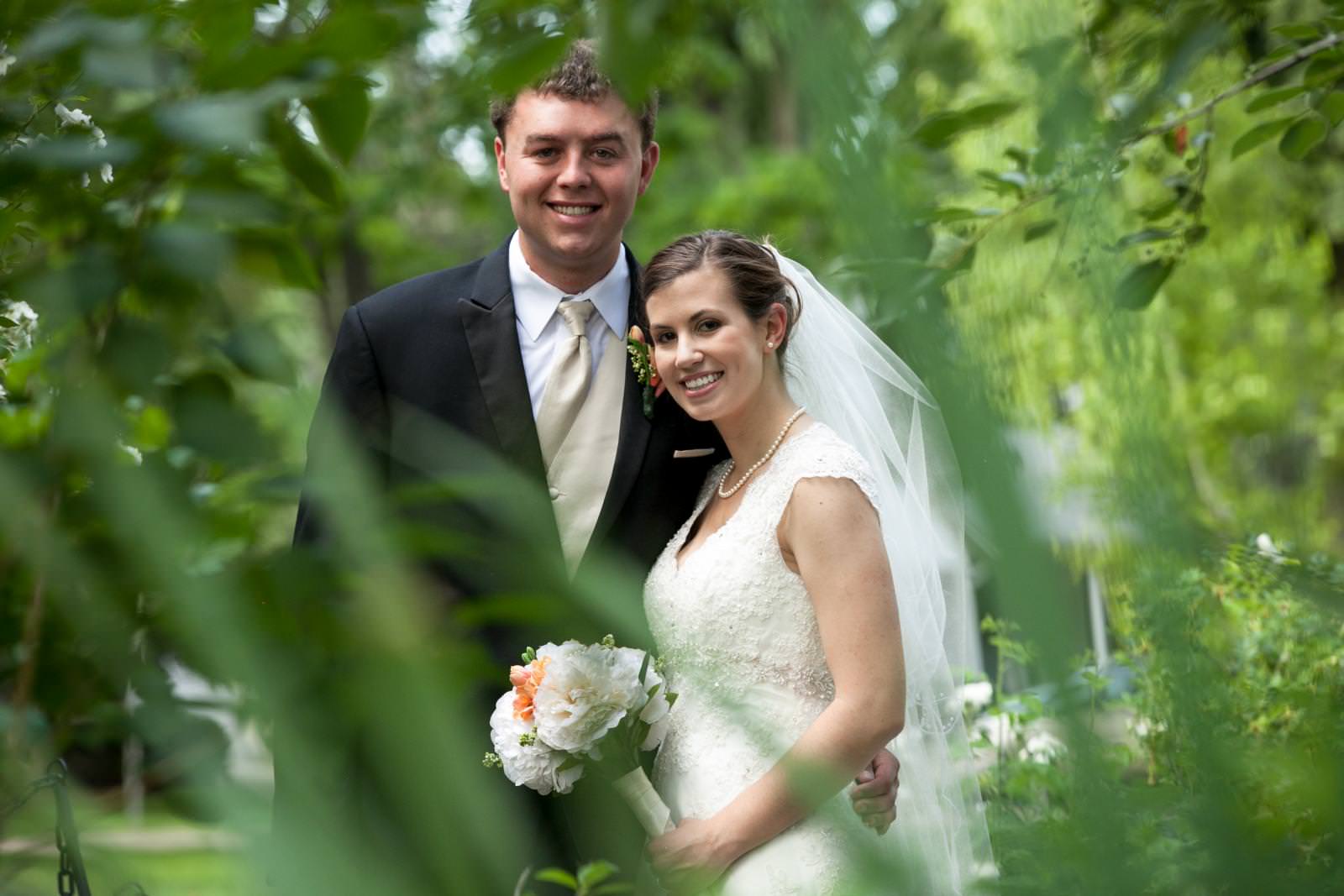 wedding couple pose amongst greenery