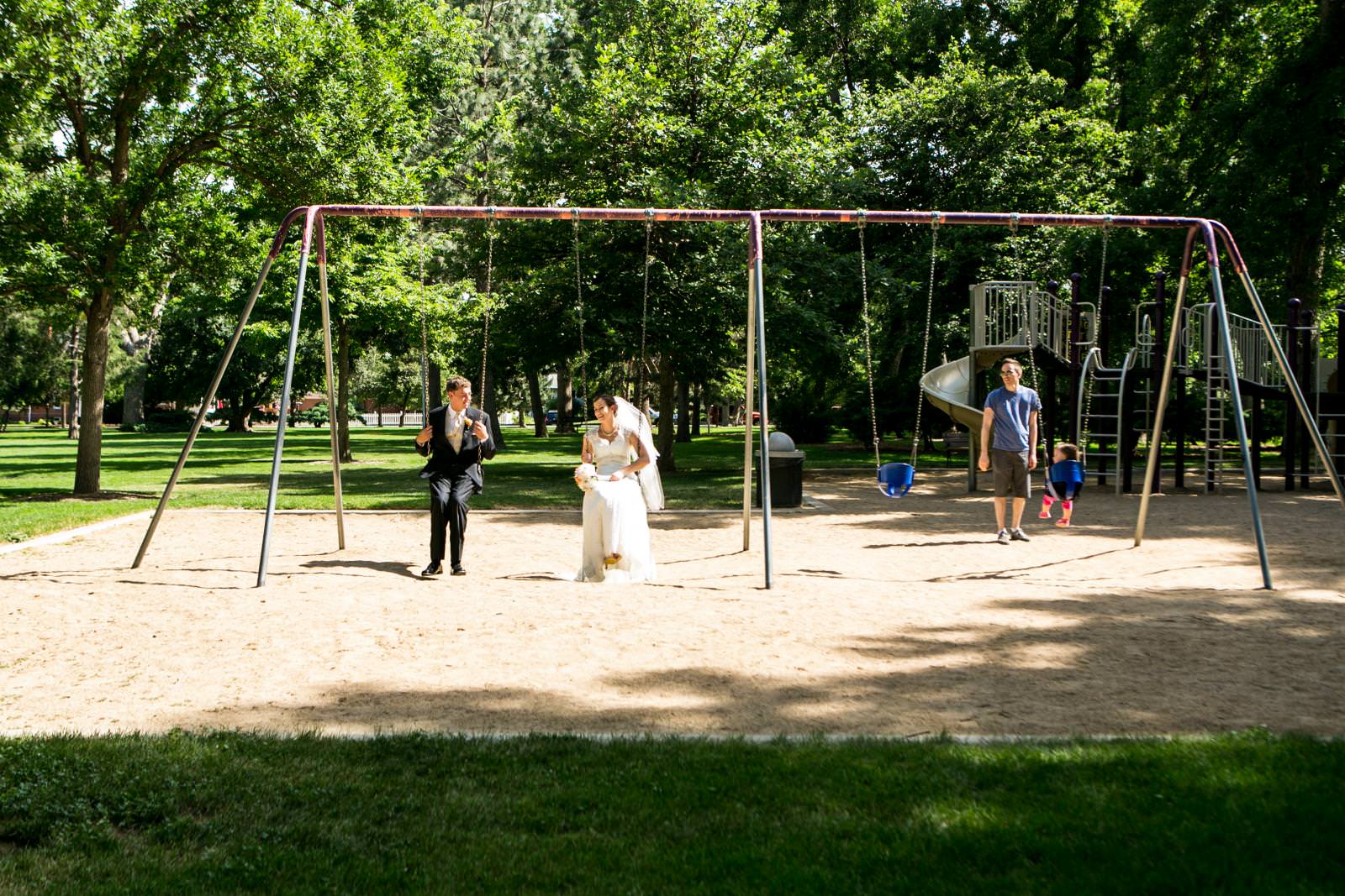 newlyweds riding swings at a park