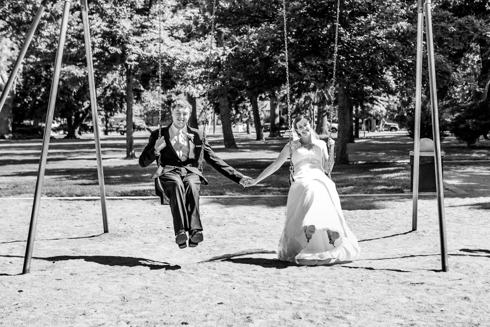 newlyweds hold hands on swings