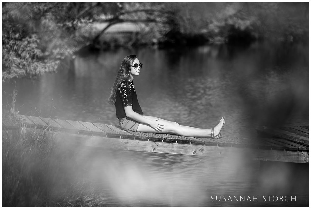 black and white of a girl sitting on a dock